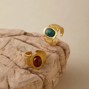Detail of vintage gold-plated rings with red and turquoise stones on natural rock base
