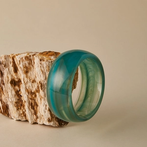 Gros plan d'un bracelet en acrylique sarcelle translucide à texture marbrée
