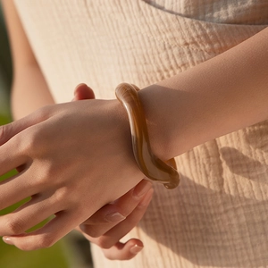 Primo piano del bracciale in acrilico ambra con design ondulato irregolare sul polso