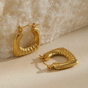 Dettaglio ravvicinato di orecchini a forma di U placcati in oro con texture a coste