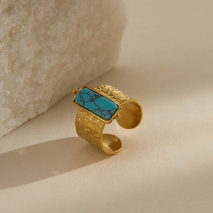 Detail of vintage gold ring featuring a wide hammered metal band and blue turquoise stone