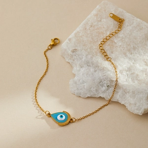 Detailed macro view of gold evil eye charm bracelet with S.STEEL engraved on tag