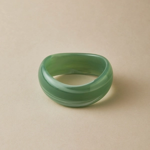Macro detail of wide translucent green acrylic bangle with white marble swirls and organic curves