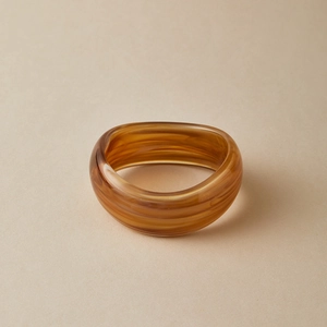 Detailed view of wide amber acrylic bangle with elegant brown marble texture finish