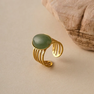 Detail of adjustable gold ring with oval green gemstone and multi-layered band