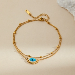 Close-up of double-layer gold stainless steel bracelet with evil eye and blue enamel