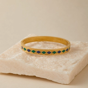 Dettaglio del bracciale rigido in acciaio dorato con smalto blu e smeraldo vintage