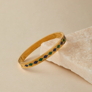 Dettaglio del bracciale dorato con motivi a rombi in smalto verde e blu scuro