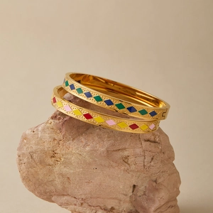 Dettaglio macro di bracciali rigidi in acciaio inossidabile dorato con smalto colorato