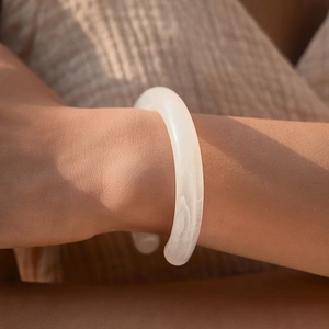 Dettaglio di un bracciale aperto in acrilico bianco con trama marmorea sul polso