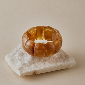 Macro shot of wide amber resin link bracelet with marble texture on white rock