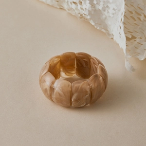 Detailed close-up of brown marble textured wide resin bangle with elastic link design
