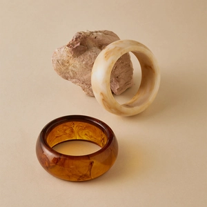 Detail of amber and cream marble acrylic bracelets on a natural stone base