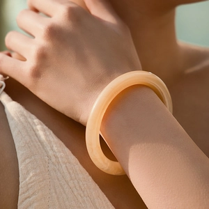 Dettaglio di un bracciale in acrilico giallo traslucido con design a onde irregolari