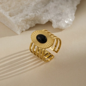 Macro shot of retro wide gold band ring with black stone and sunburst engraving detail