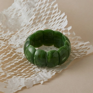 Detailed view of green resin chunky bracelet with jade-like texture on white paper