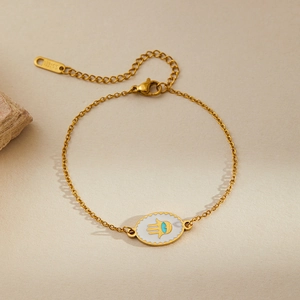 Detail of gold-plated stainless steel Hamsa hand bracelet with blue evil eye charm