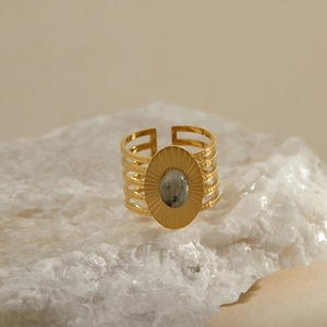 Macro shot of retro gold-plated ring with oval grey stone and tiered cutout band