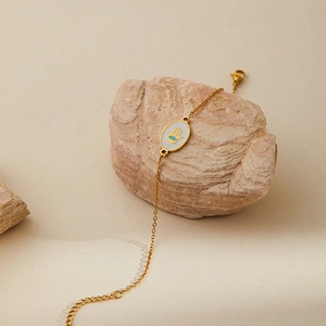Detail of gold Hamsa Hand bracelet with blue Evil Eye charm on a natural stone