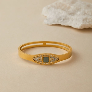 Dettaglio del bracciale dorato con intarsio in turchese e pietre bianche su sfondo pietra