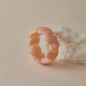 Detailed close-up of pink marble resin stretch bracelet leaning on white crystal stones