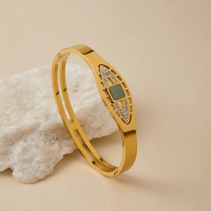 Dettaglio di un lussuoso bracciale dorato con gemma blu e design a forma di occhio