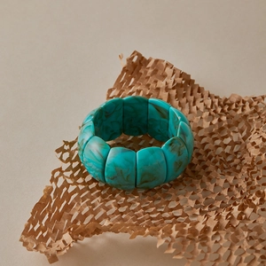 Macro detail of wave-shaped wide resin bangle with green marble texture and smooth finish