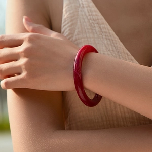 Dettaglio di un bracciale rosso traslucido con texture marmorea su un polso femminile