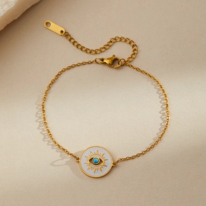 Detailed macro of golden Evil Eye bracelet with blue turquoise bead on beige stone surface