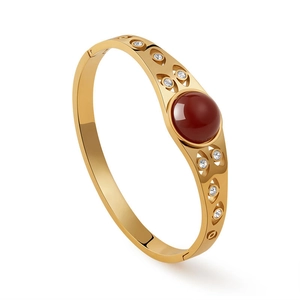 Dettaglio del bracciale dorato con gemma rossa e pavé di zirconi bianchi luminosi