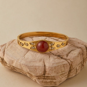 Dettaglio del bracciale in acciaio dorato con pietra rossa e zirconi bianchi lucidi