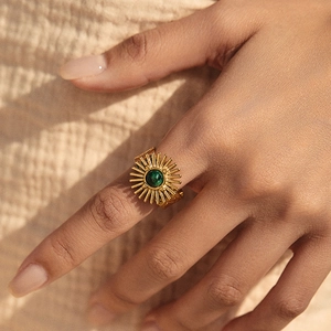 Vintage gold sunburst ring with green turquoise stone on textured fabric background