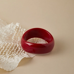 Macro detail of wine red acrylic resin wide bangle with glossy wavy texture