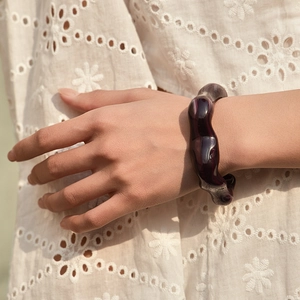 Dettaglio del bracciale irregolare in acrilico viola intenso sul polso di una modella