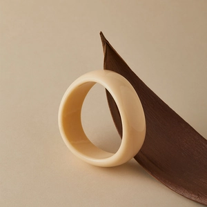 Macro detail of tortoiseshell acrylic bangle with cream marble texture and polished finish