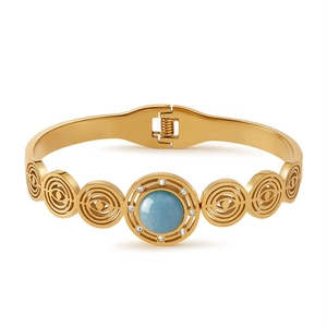 Vista macro del bracciale dorato con pietra blu e design a spirale traforato