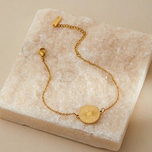 Macro detail of gold plated evil eye bracelet with radial sunburst pendant and lobster clasp