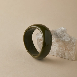 Detail of a dark olive green acrylic resin wide bangle with a polished marble texture