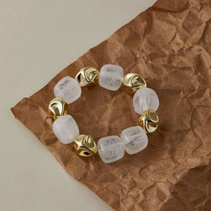 Détail d'un bracelet vintage en résine avec blocs dorés sur du papier froissé