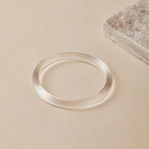 Nahaufnahme eines klaren Acryl-Armreifs mit polierten Schrägkanten im minimalistischen Stil