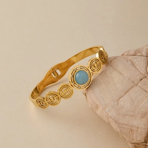 Dettaglio di bracciale dorato con pietra turchese e design a cerchi concentrici cavi