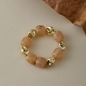Détail de perles en résine ambrée marbrée et de perles en métal doré sur un bracelet perlé