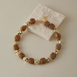 Dettaglio della collana con perle quadrate in marmo marrone e inserti in metallo dorato