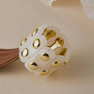 Macro detail of marble resin segments with golden metal studs on elastic bracelet