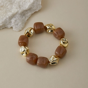 Gros plan de perles marbrées brunes et d'accents dorés irréguliers sur un bracelet rétro