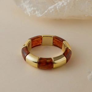 Detail of sectional amber resin and gold metal bangle with polished tortoiseshell finish