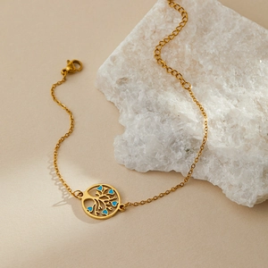 Detailed shot of gold-plated tree of life bracelet with blue hearts on white mineral stone