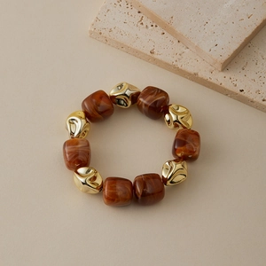 Vue détaillée des perles de résine marbrée et accents dorés irréguliers sur un bracelet chic