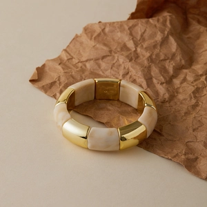 Chic gold metal and beige marble acrylic elastic bracelet on a minimalist neutral backdrop
