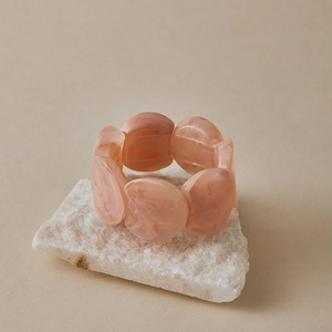 Gros plan d'un bracelet élastique en perles acryliques marbrées rose sur pierre